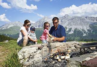 Famille faisant un barbecue sur un foyer en plein air dans les montagnes des Grisons avec panorama alpin