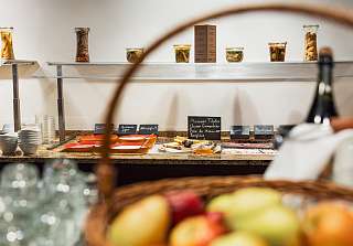 Breakfast buffet at Sunstar Hotel Arosa with fruit basket, preserving jars, labelled dishes and a varied selection on a granite counter