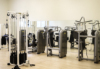 Salle de fitness lumineuse avec équipements de musculation et de cardio modernes ainsi qu'un mur de miroirs au Sunstar Hotel Arosa.